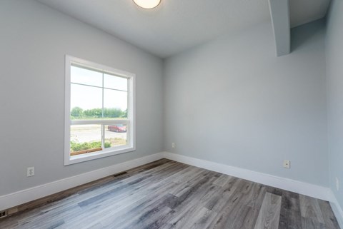 an empty room with wood floors and a window