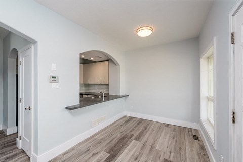 the living room and kitchen of a new home with white walls and wood flooring