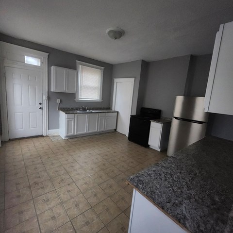 A kitchen with a granite counter and white cabinets.