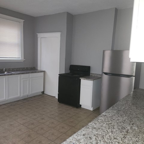 A kitchen with a black dishwasher and a white refrigerator.