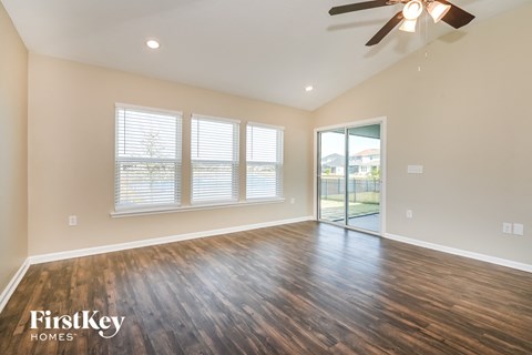 the spacious living room with hardwood flooring and a ceiling fan