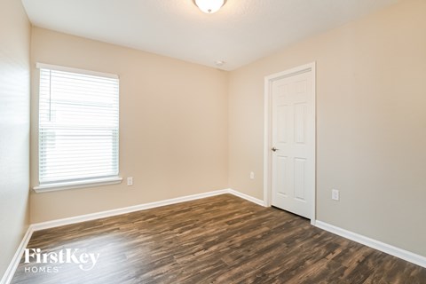 a bedroom with a white door and wood flooring
