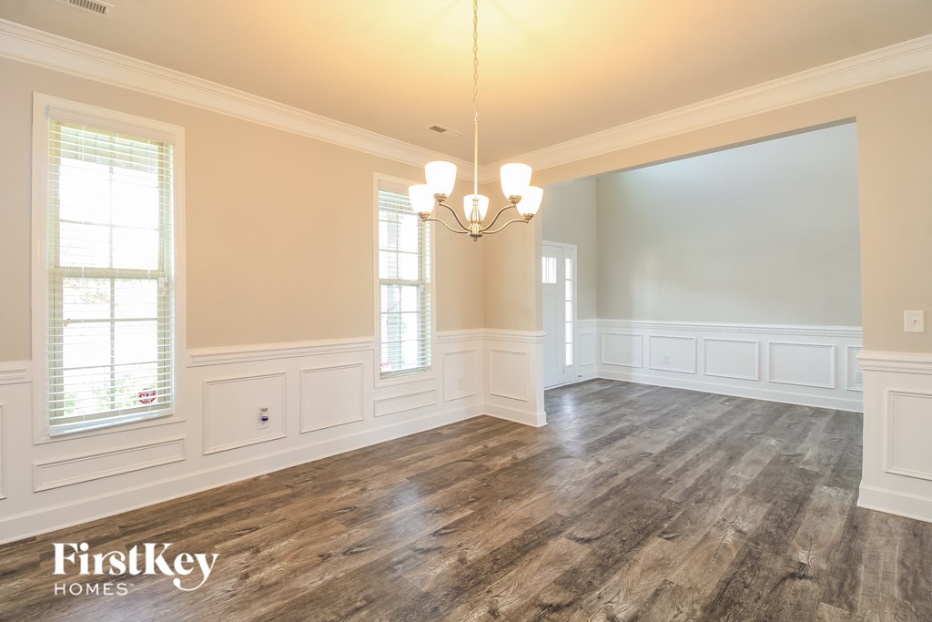 an empty living room with wood floors and a chandelier