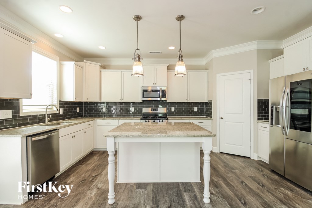 a kitchen with white cabinets and a marble counter top