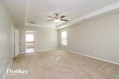 a spacious living room with carpet and a ceiling fan