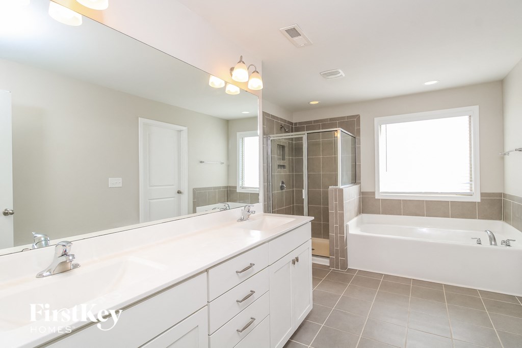 a white bathroom with a tub and a sink and a mirror