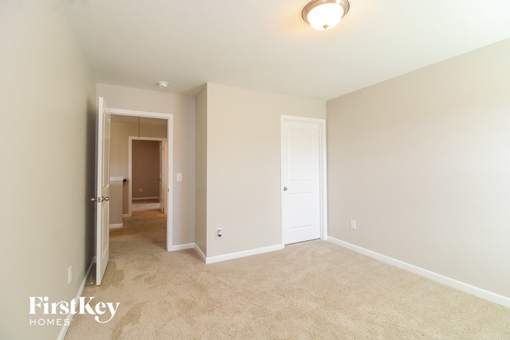 a master bedroom with carpeted flooring and a door to a hallway with a