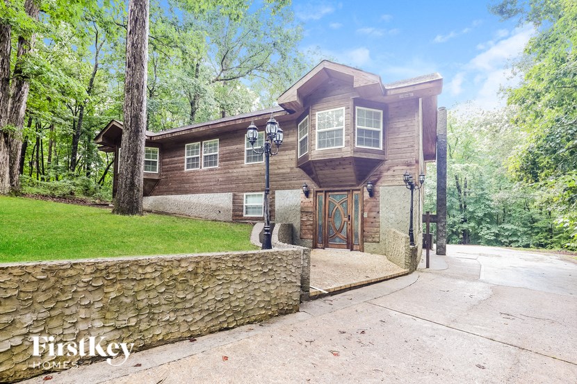 the front of a house with a driveway and a stone wall