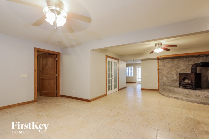 a large empty living room with a fireplace and a ceiling fan