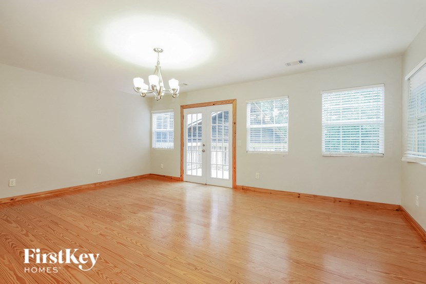 an empty living room with wood flooring and a door to the dining room