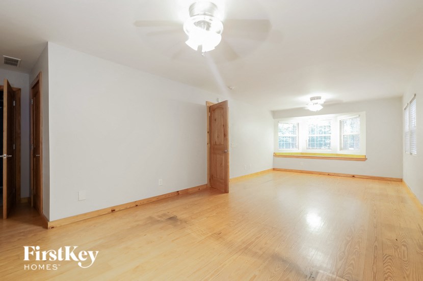an empty living room with wood flooring and a ceiling fan