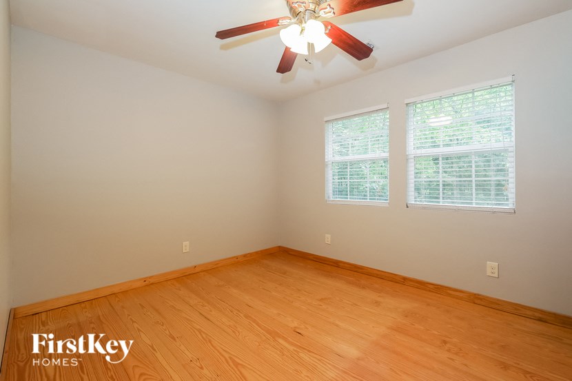 a bedroom with wood floors and a ceiling fan