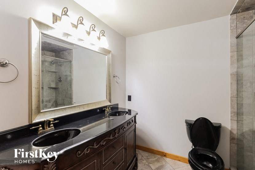 a bathroom with a black toilet and a sink and a mirror
