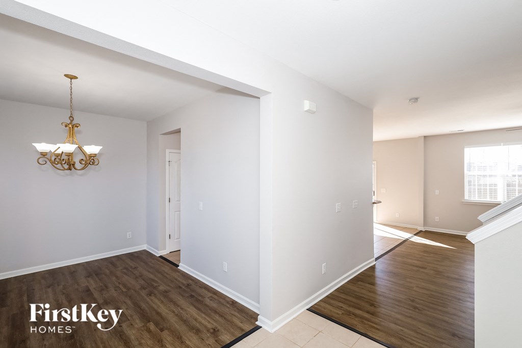 a living room and dining room with white walls and wood floors