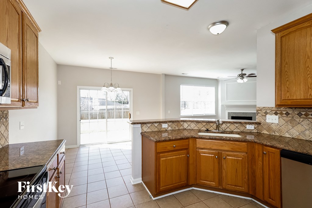 a kitchen with wooden cabinets and tiled floors and a door to a patio
