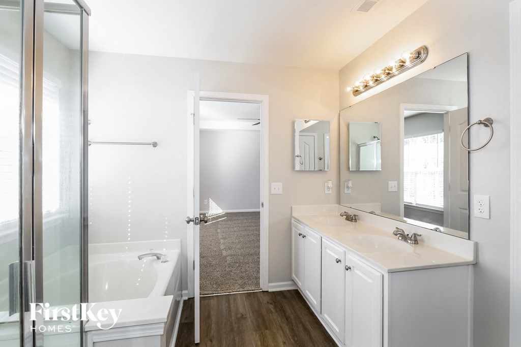 a white bathroom with a tub and a sink and a mirror