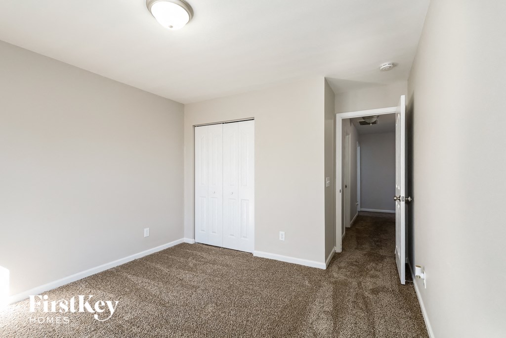 a bedroom with carpeted flooring and white walls and a door to a hallway