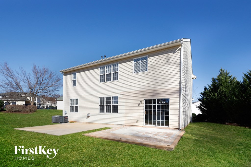 the side of a white house with a ramp in the grass