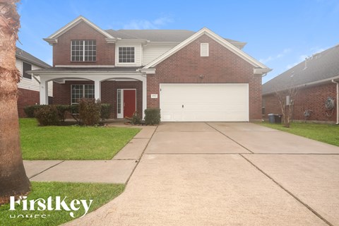 A brick house with a red door and a garage door.