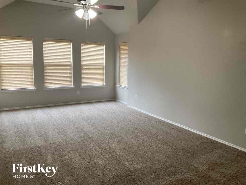 an empty living room with three windows and a ceiling fan