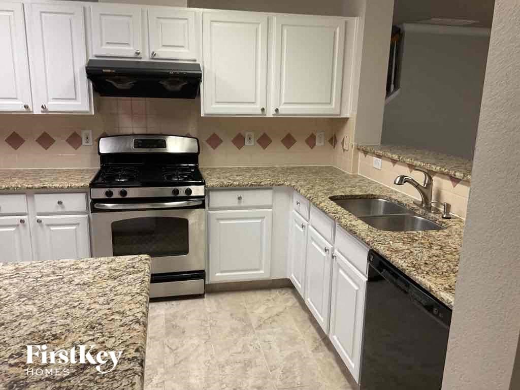 a kitchen with white cabinets and a stove and a sink