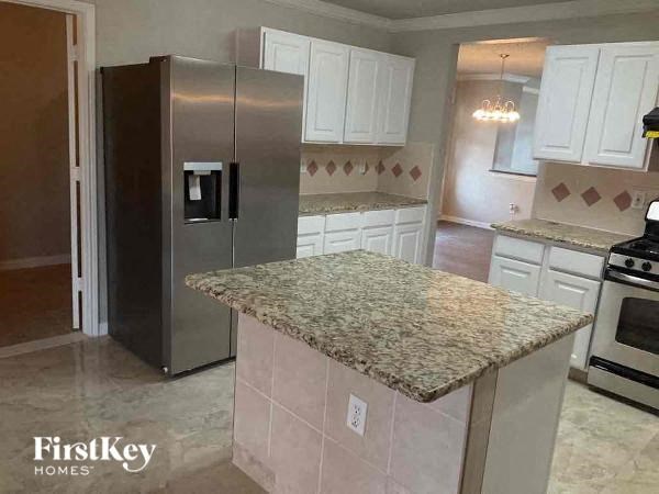 a kitchen with a granite counter top and a stainless steel refrigerator
