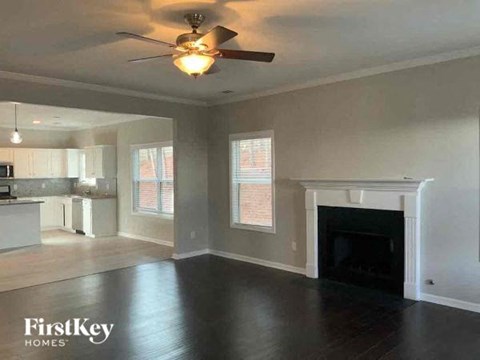 A spacious living room with a fireplace and a ceiling fan.