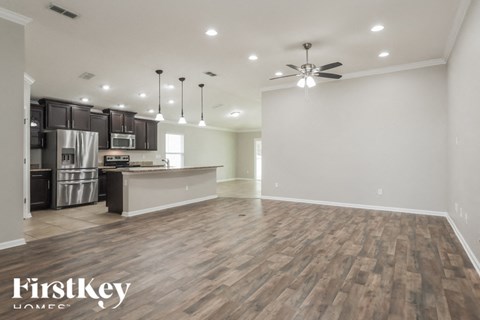 A spacious kitchen with dark wood floors and a ceiling fan.