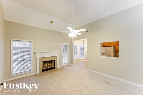 A spacious room with a fireplace and a ceiling fan.