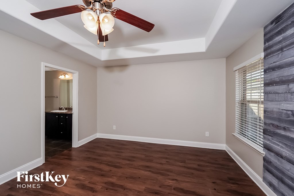an empty living room with a ceiling fan and a window