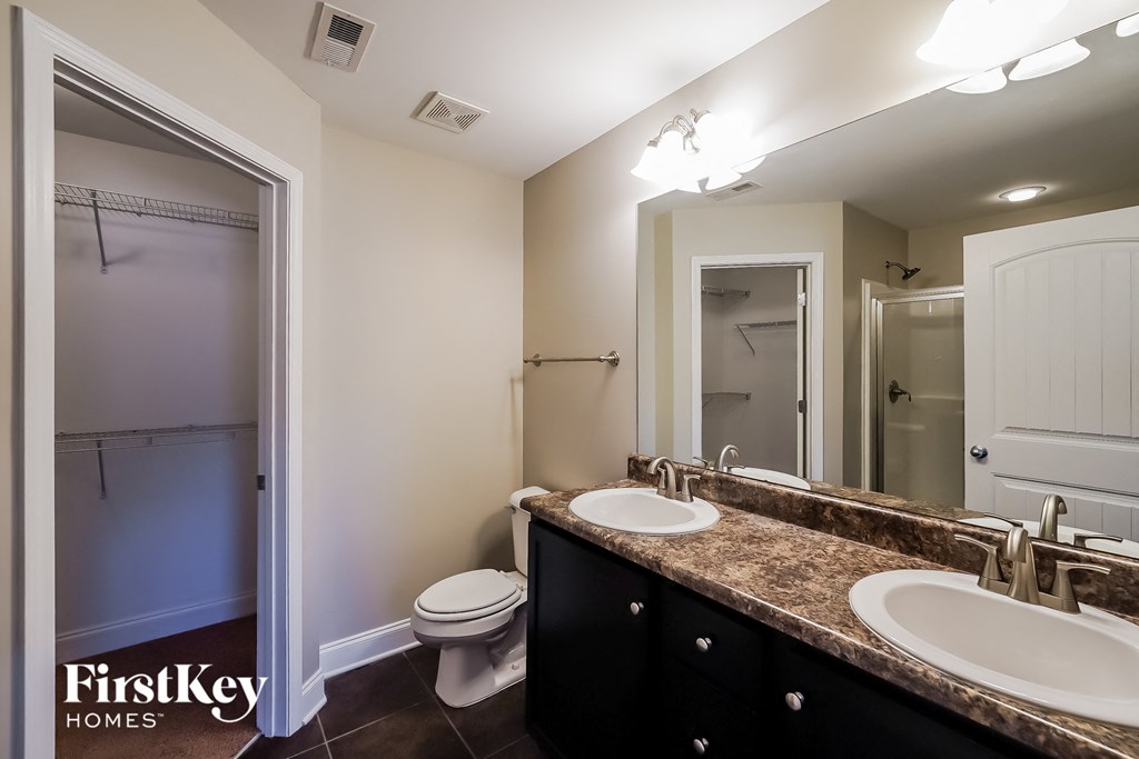 a bathroom with two sinks and a toilet and a shower