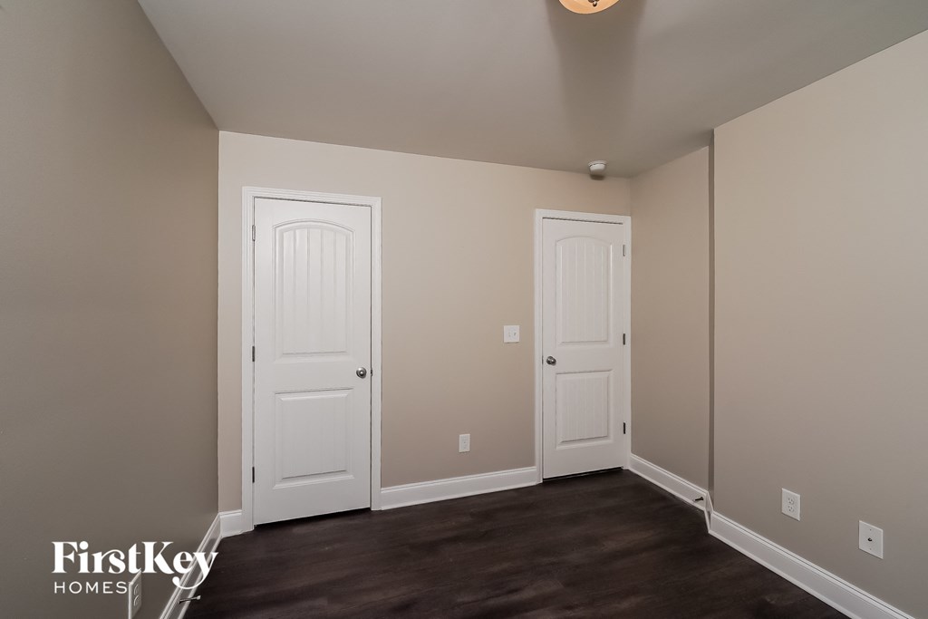 a bedroom with two white doors and a dark wood floor