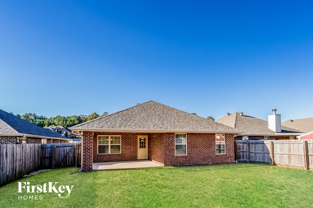 a small brick house with a yard and a fence