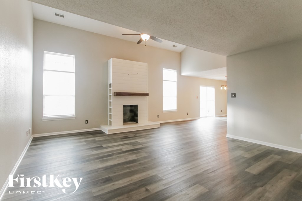A spacious room with a fireplace and wooden floors.