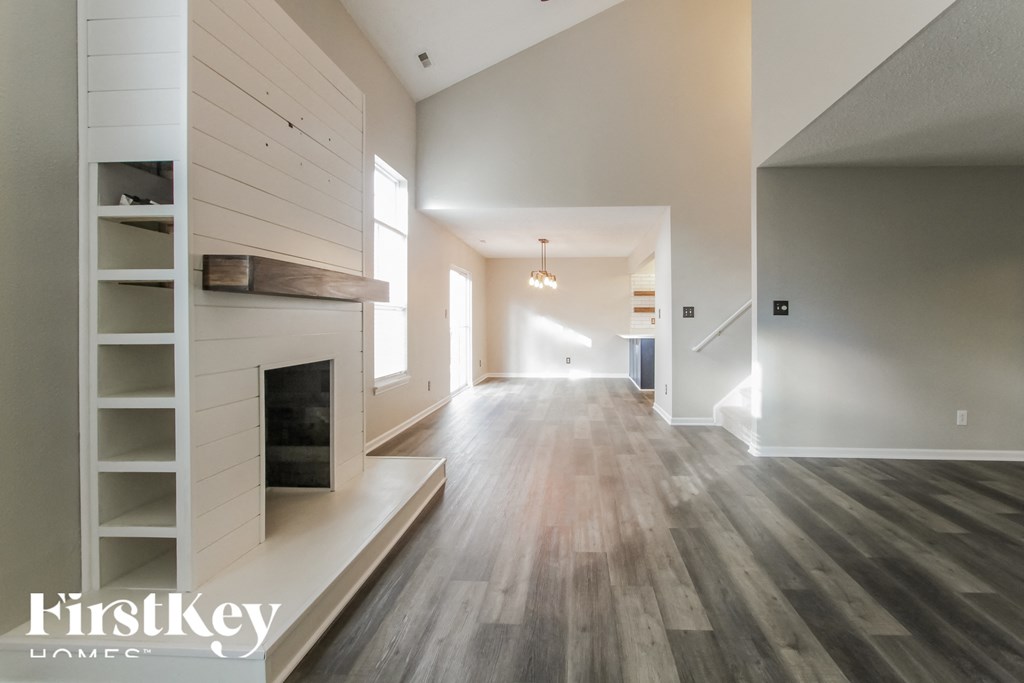 A spacious hallway with wooden floors and white walls.