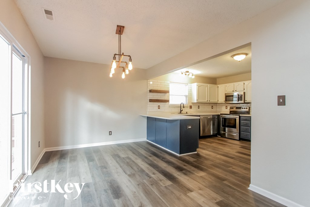 A large open space with a kitchen in the background and a wooden floor.