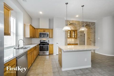 a kitchen with a marble counter top and wooden cabinets