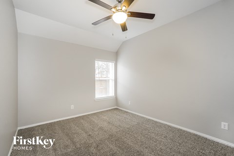 the spacious living room with ceiling fan and carpet