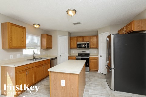 A kitchen with wooden cabinets and a black refrigerator.