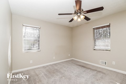 a living room with carpet and a ceiling fan