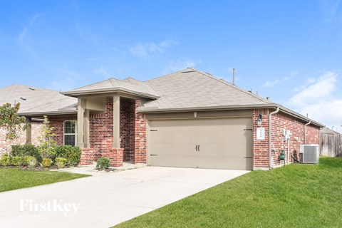 a brick house with a garage door and a lawn