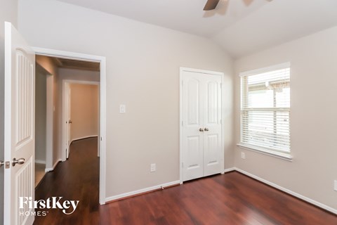 a bedroom with wood floors and a door and a closet
