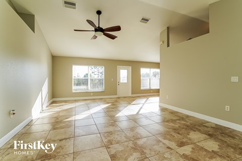 an empty living room with tile floors and a ceiling fan