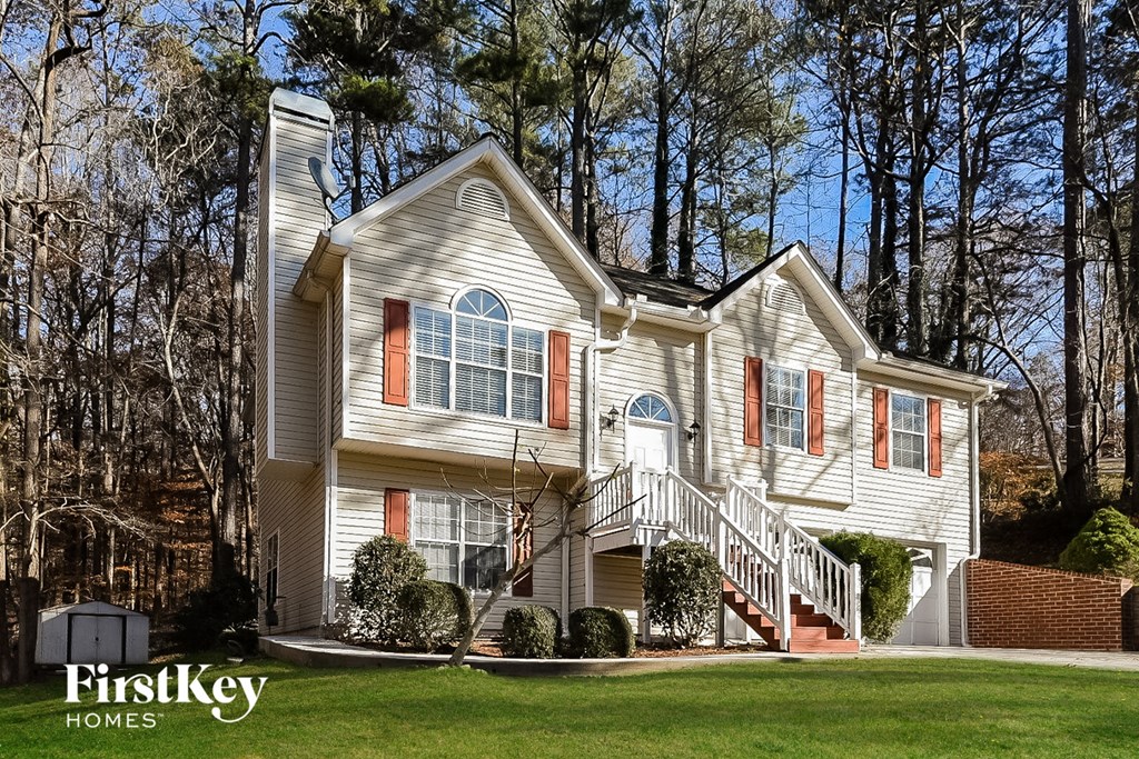 a white house with red shutters and a lawn
