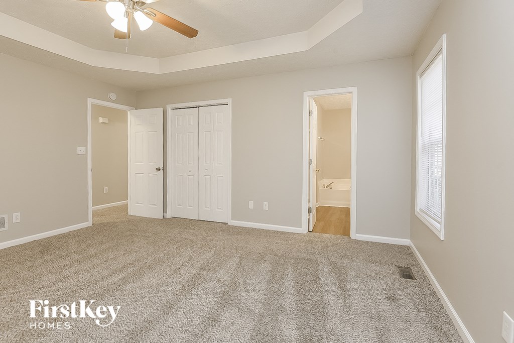 a spacious living room with carpet and a ceiling fan