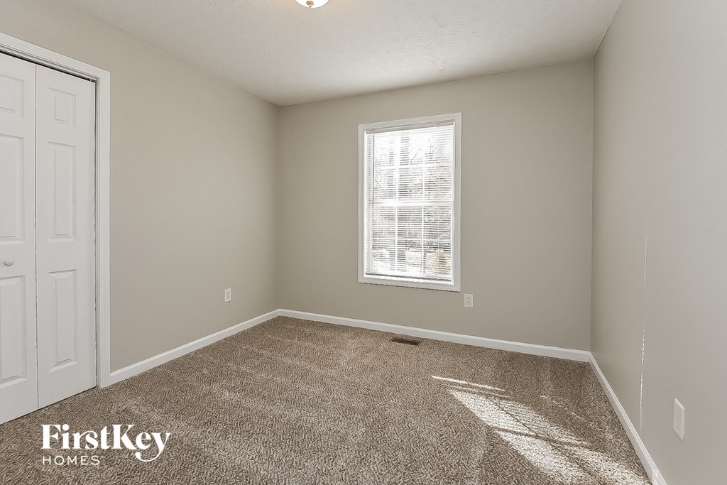 a bedroom with carpet and a window and a white door