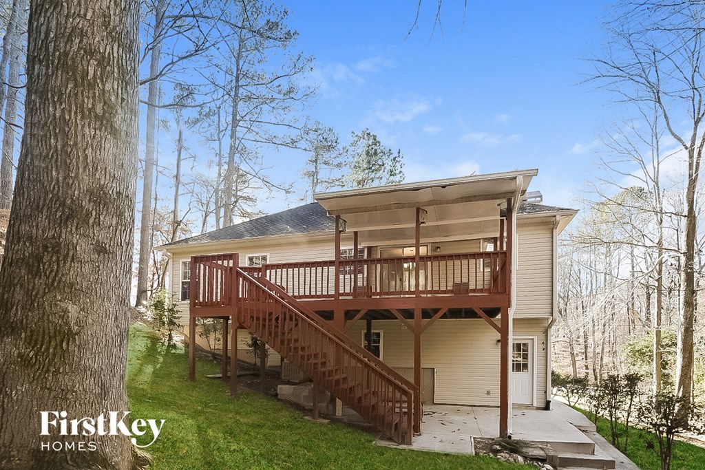 the back of a yellow house with a red deck