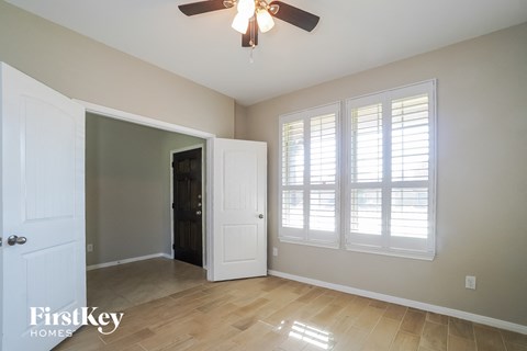 an empty living room with a ceiling fan and windows