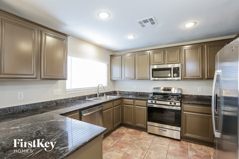 A kitchen with brown cabinets and a black counter top.