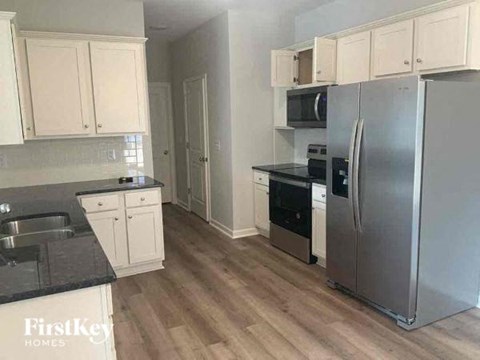 A kitchen with a refrigerator, sink, and cabinets.